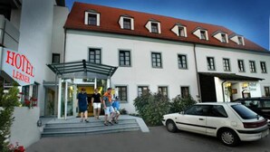 A hotel with a red roof, a glass entrance, and a white facade. - Gasthof Lerner (Freising)