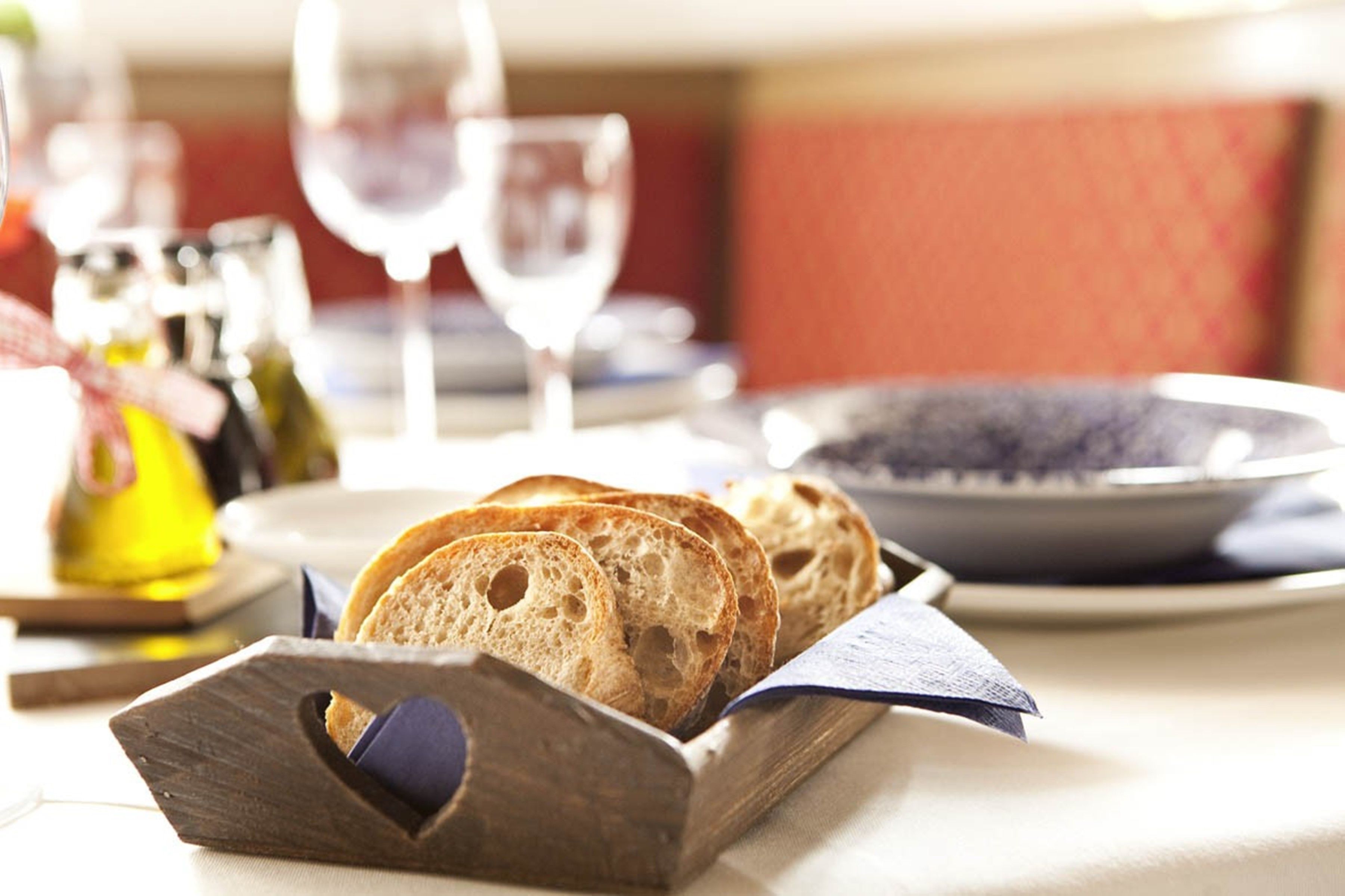 A wooden bread basket with slices of bread on a table.