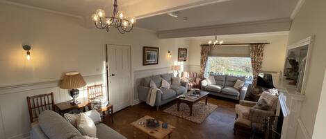 A living room with a sofa, armchairs, a coffee table, and a chandelier.