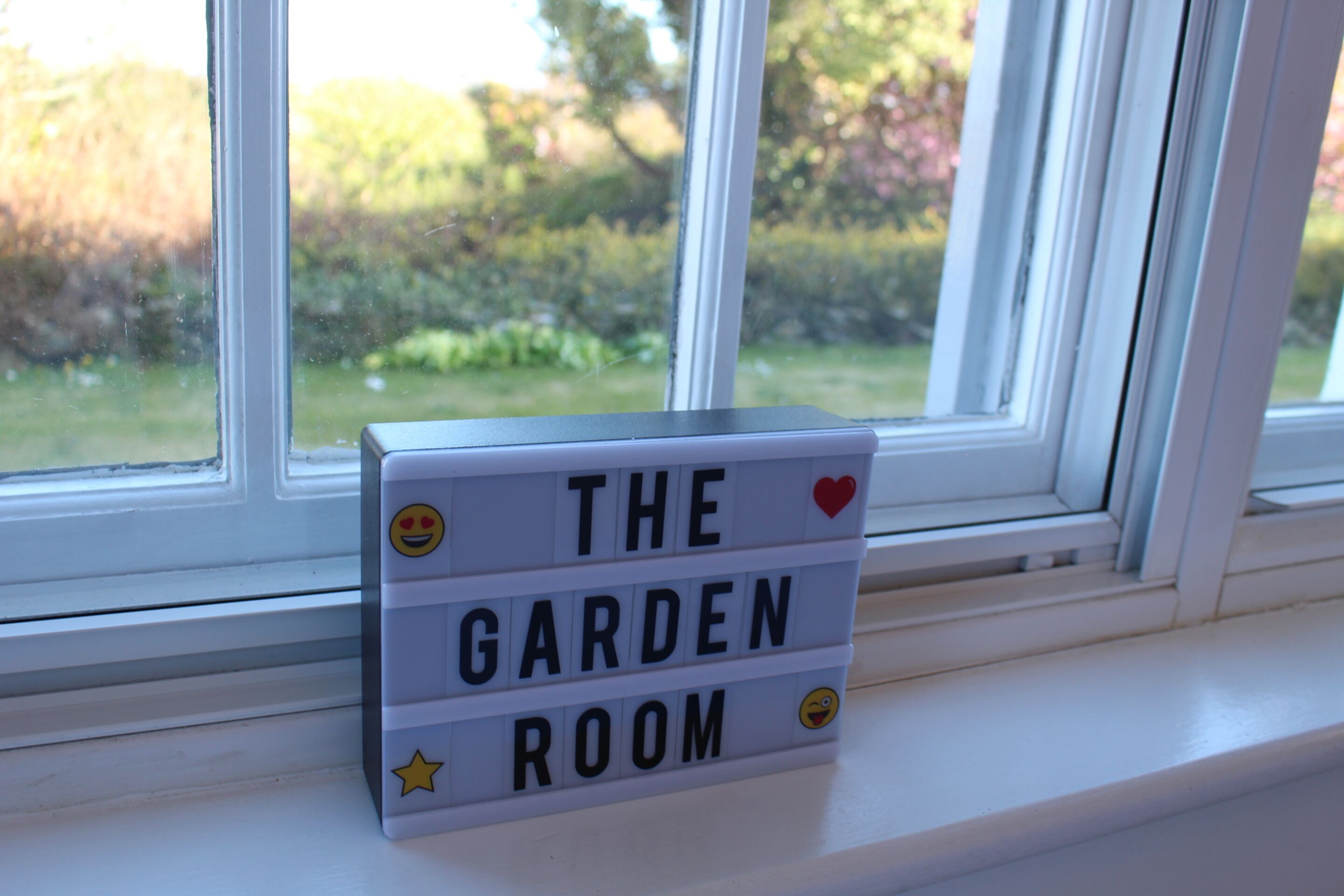A window sill with a sign that reads "THE GARDEN ROOM."