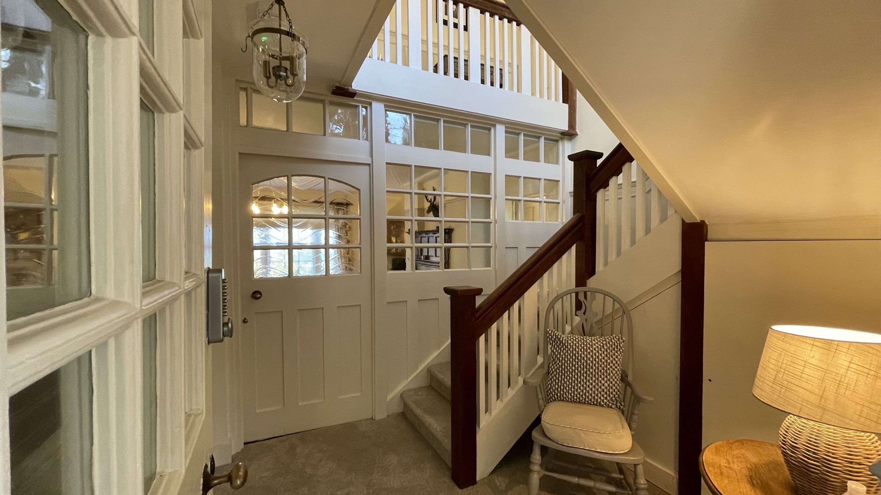 Un escalier avec une rampe en bois et une chaise en bas.