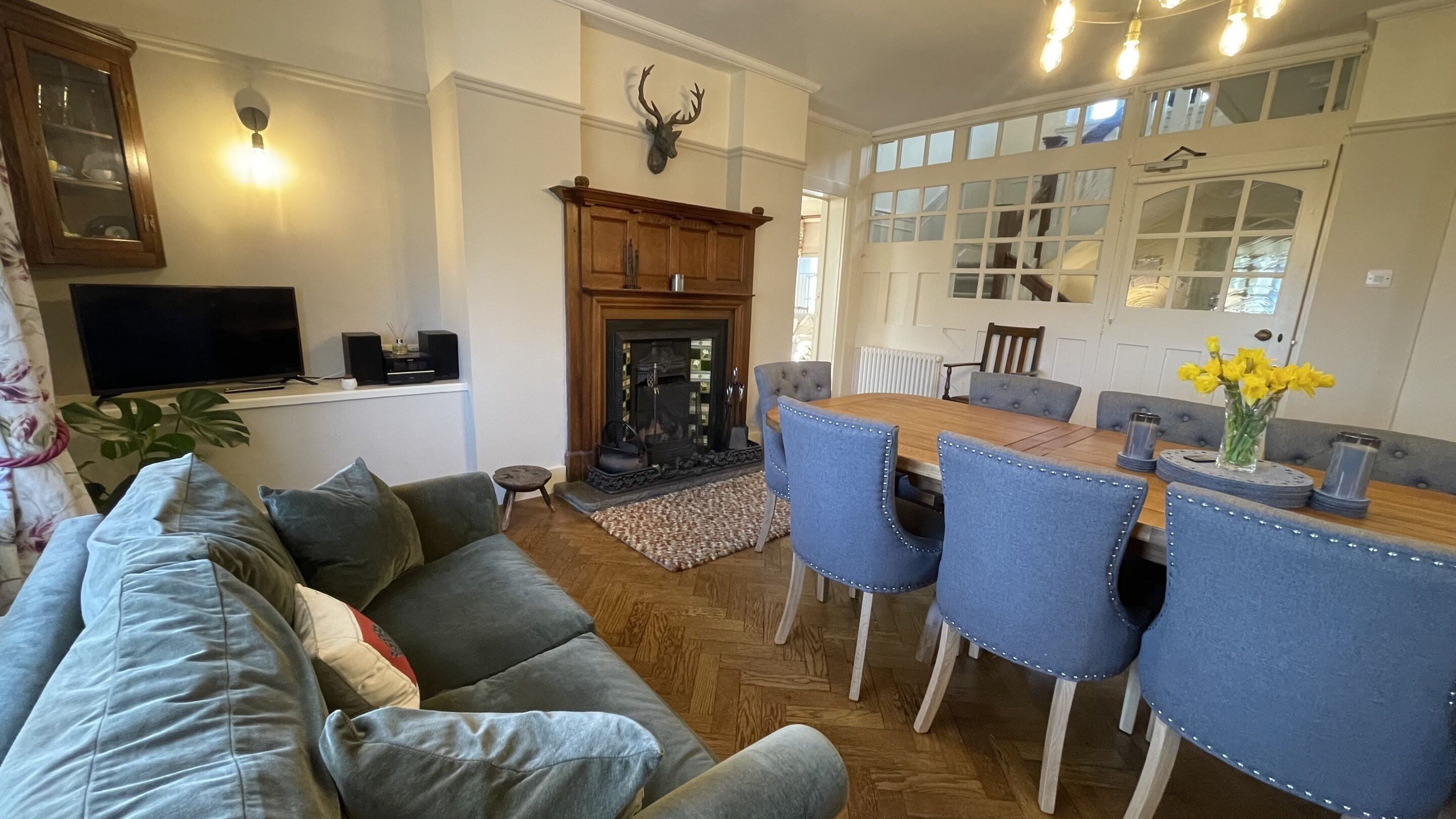 A living room with a sofa, dining table, chairs, a fireplace, and a television.