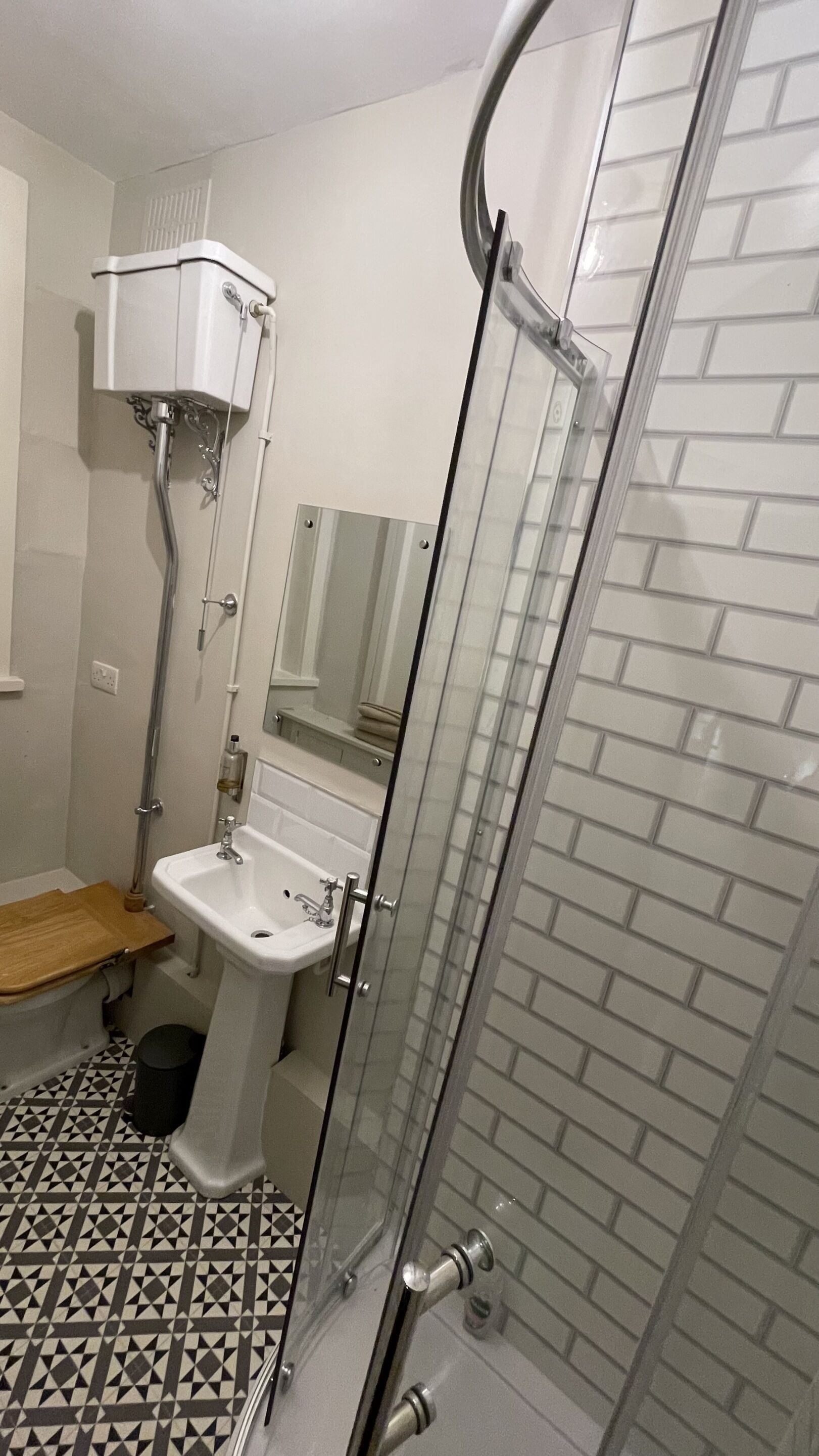 Une salle de bain avec une douche à parois de verre, un lavabo sur colonne et des toilettes.