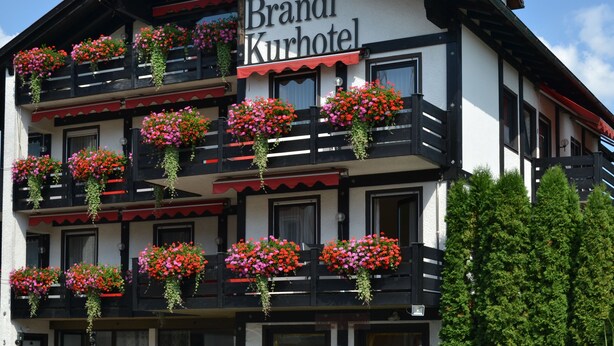 A two-story building with the sign "Bradl Kurhotel" indicating it is a hotel. The building features balconies with flower boxes and a traditional architectural style. - Hotel Brandl (Bad Woerishofen)