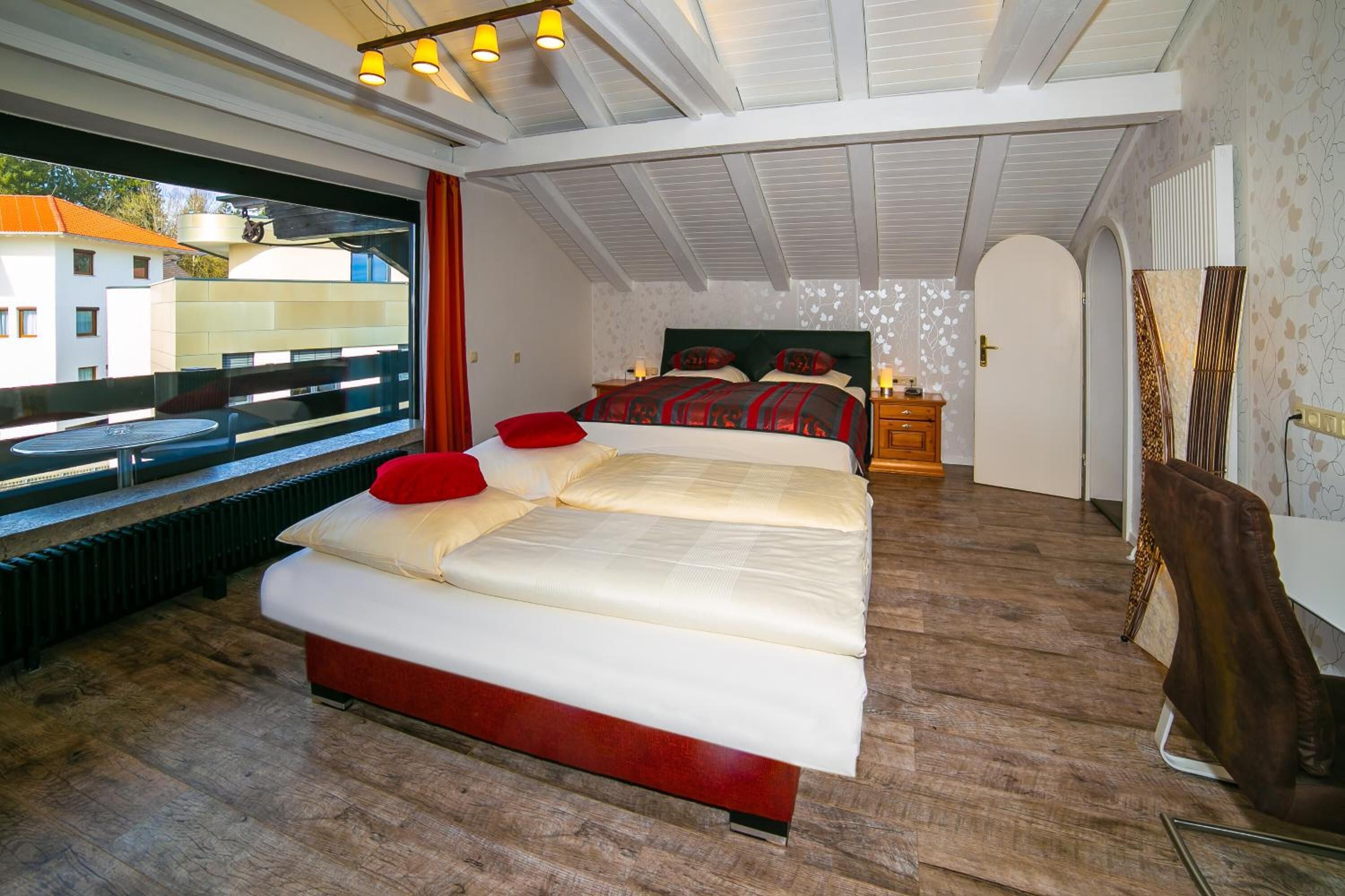 Ein Schlafzimmer mit einem großen Bett, einem Fenster und Blick auf Gebäude.