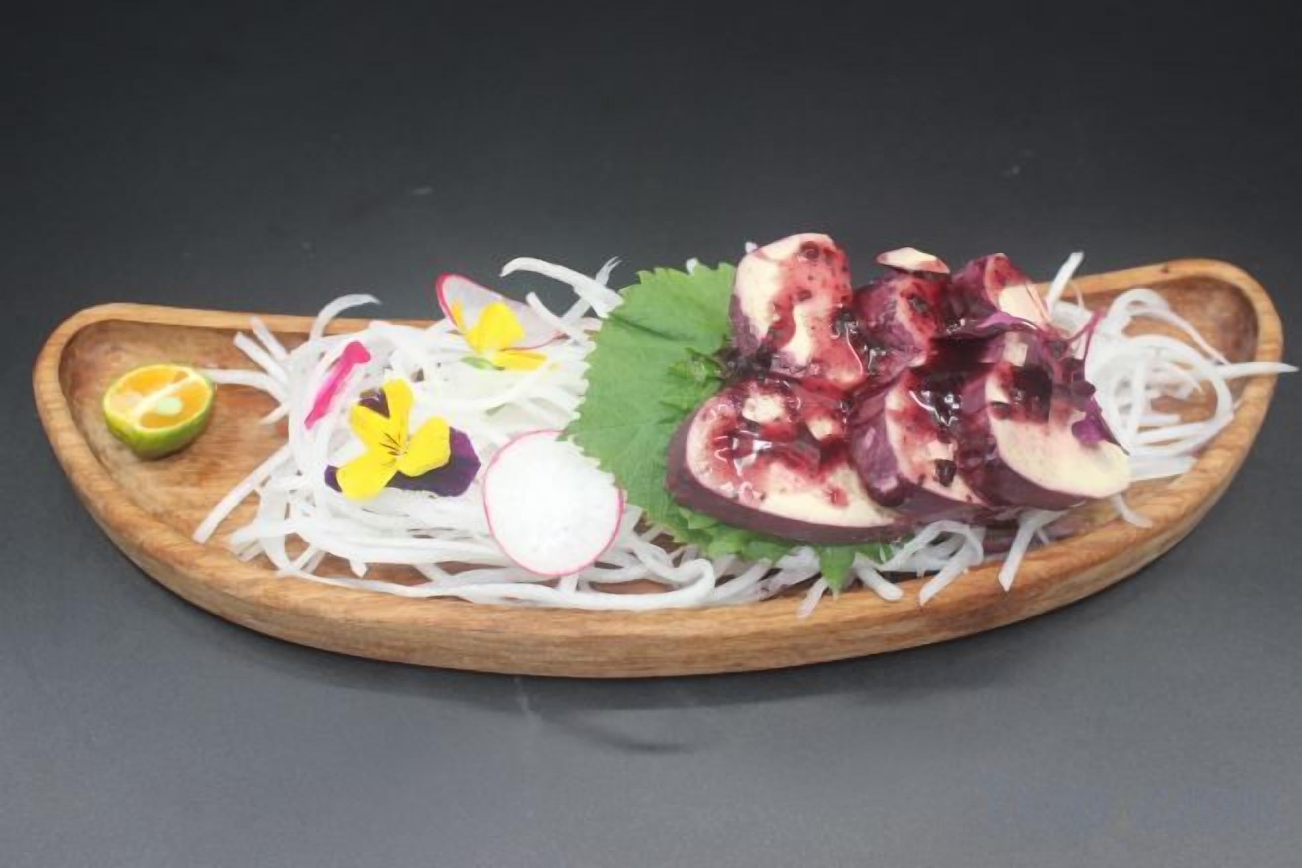 Un plato de madera con frutas y verduras cortadas.