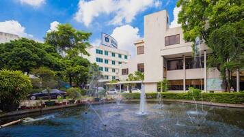 A courtyard with a fountain, surrounded by trees and modern buildings.