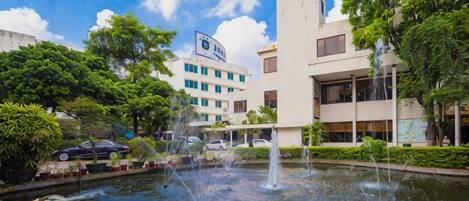 A courtyard with a fountain, surrounded by trees and modern buildings.