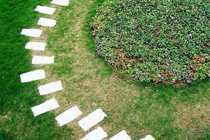 A garden with a circular hedge and a stone pathway. - Dongguan Hotel (Dongguan)