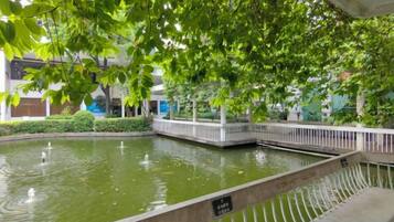 Un espace intérieur paisible agrémenté d’une fontaine, entouré d’une végétation luxuriante et d’une rambarde blanche.