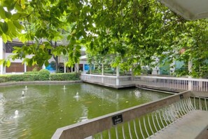 A tranquil indoor water feature with a fountain, surrounded by lush greenery and a white railing. - Dongguan Hotel (Dongguan)