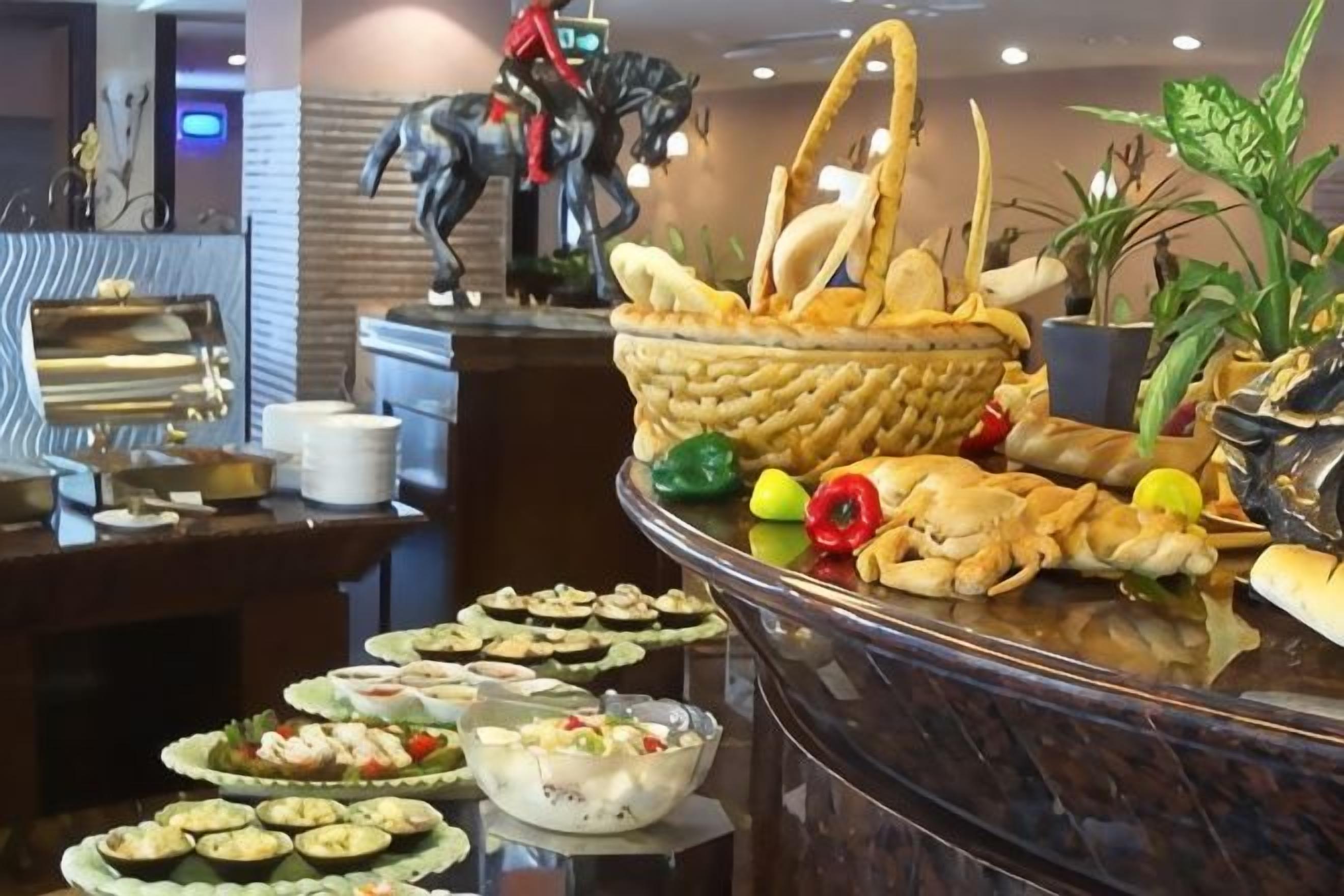 En buffet med forskellige retter, en dekorativ heste statue og potteplanter.