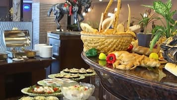 En buffet med forskellige retter, en dekorativ heste statue og potteplanter.