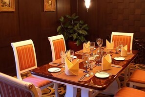 A dining table set for four with chairs, a potted plant, and a chandelier. - Dongguan Hotel (Dongguan)