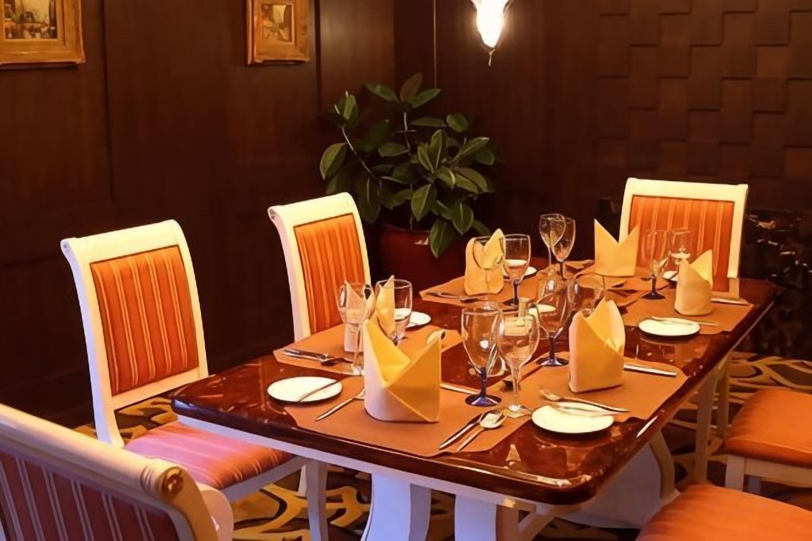 A dining table set for four with chairs, a potted plant, and a wall-mounted light fixture.