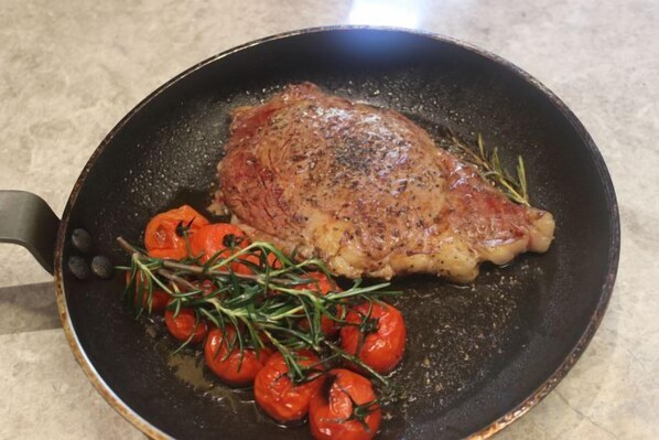 Una bistecca con rosmarino e pomodorini in padella.