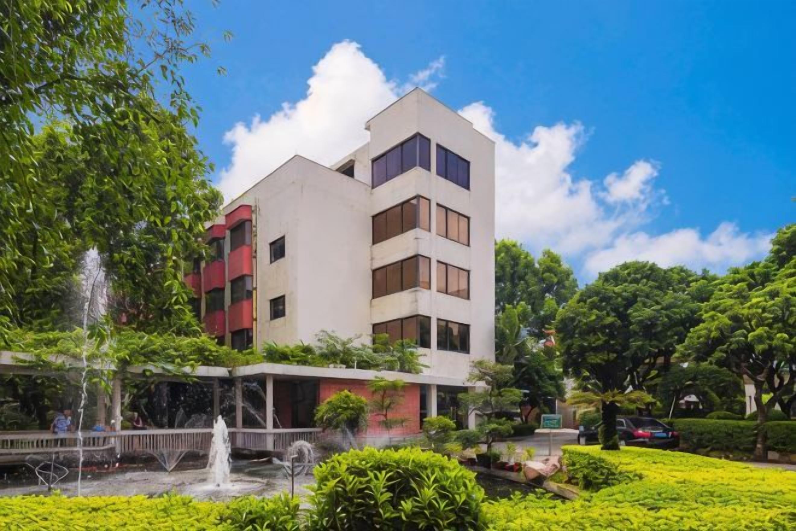 A multi-story building with a courtyard, a fountain, and lush greenery.