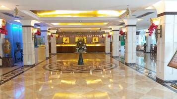 Un hall de hotel con una recepción, un diseño circular en el suelo y una columna central.