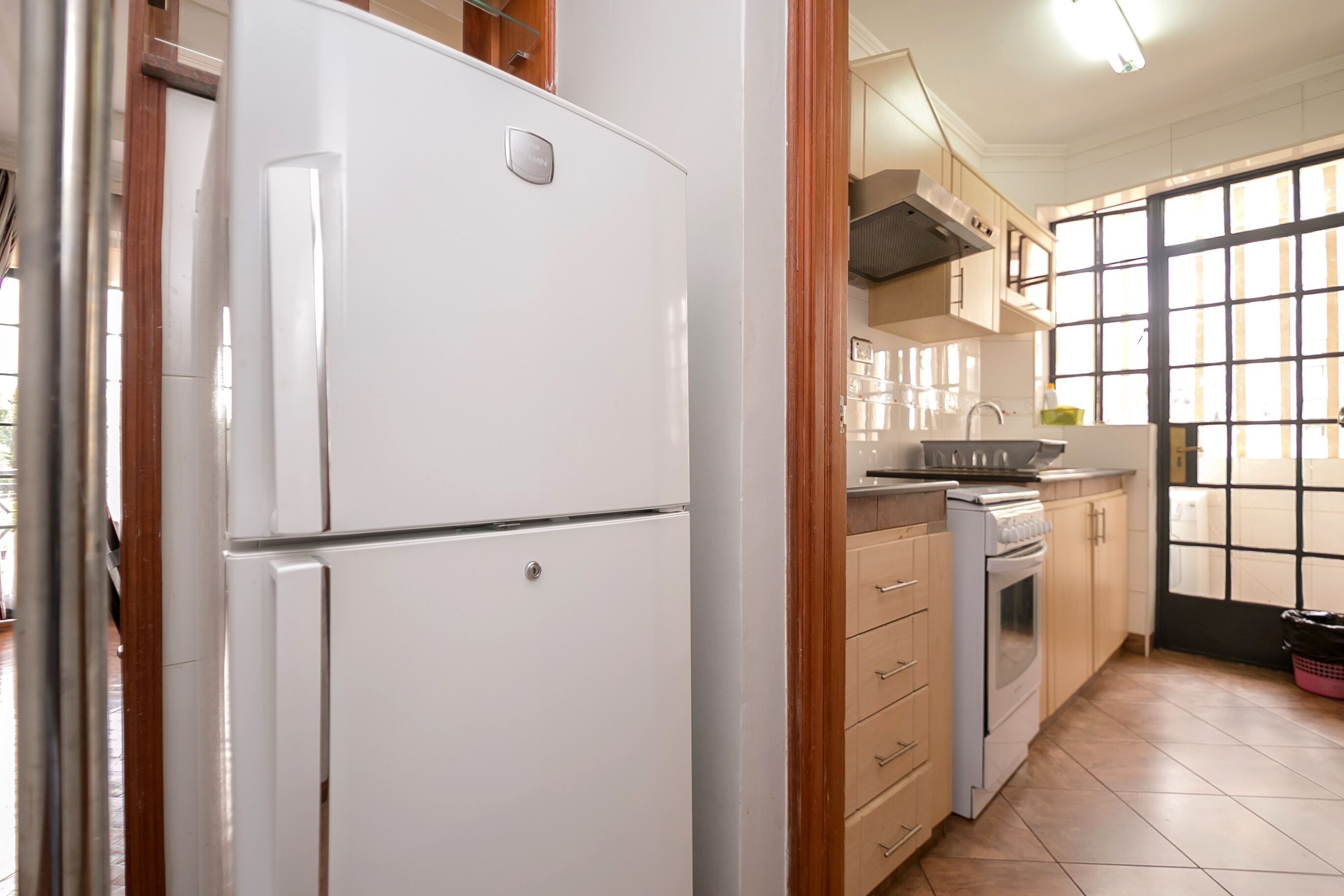 A kitchen with a white refrigerator, a stove, and wooden cabinets.