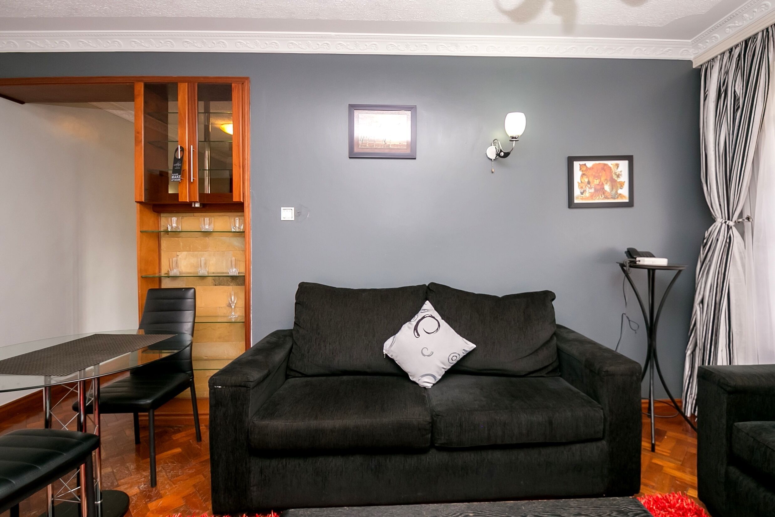 A living room with a dark sofa, a glass coffee table, and a dining area with chairs and a table.