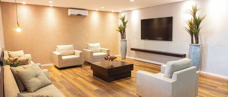 Una sala de estar moderna con un sofá, dos sillones, una mesa de centro y un televisor de pantalla plana montado en la pared.