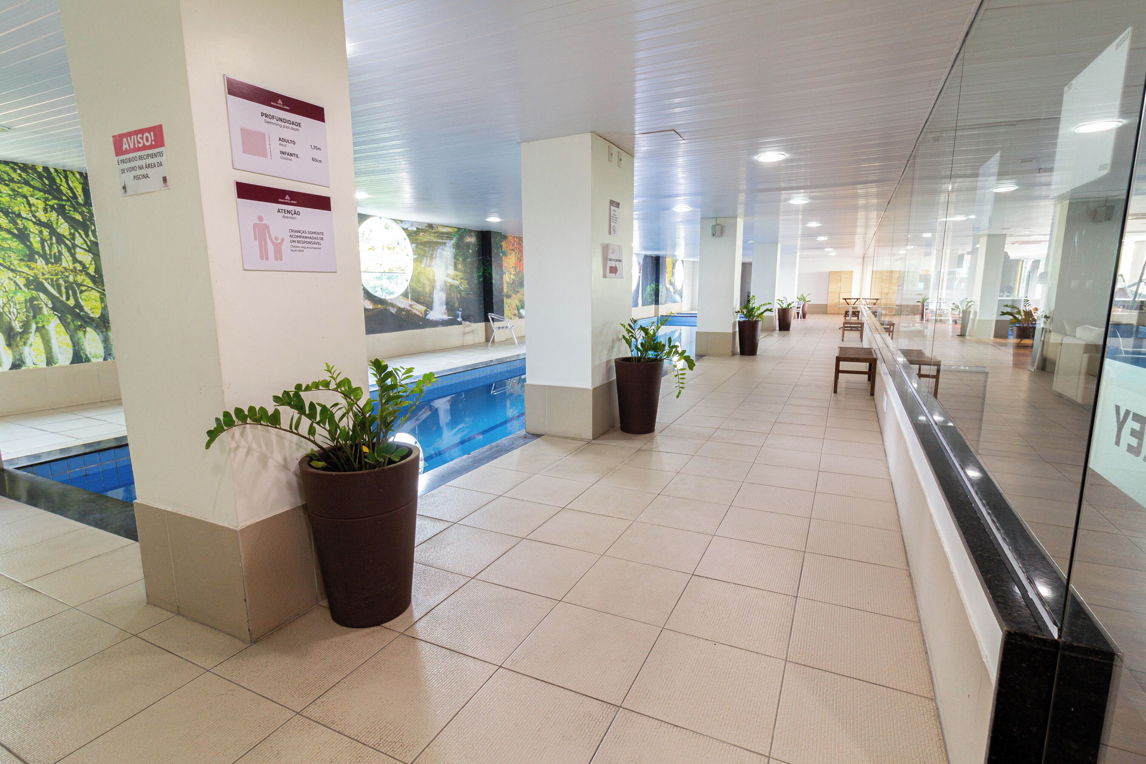 A spacious lobby with a pool, potted plants, and informational signs.