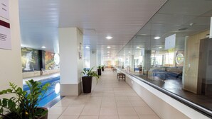 A corridor with a pool, potted plants, and a seating area.