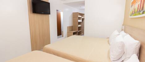 A hotel room with a bed, a TV mounted on the wall, and a painting on the wall.