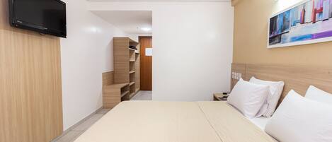 Una habitación de hotel moderna con una cama grande, un televisor de pantalla plana montado en la pared y un cuadro sobre la cama.