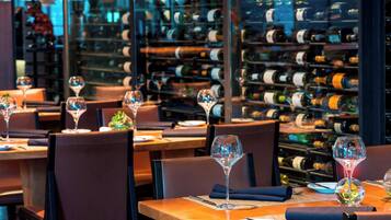 A restaurant with tables set for dining, each with a wine glass and a plate.