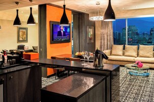 Una sala de estar moderna con cocina, una televisión grande y vistas a la ciudad.