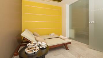 Un cuarto de spa con pared amarilla, una camilla de masaje y una mesita con aperitivos y una tetera.