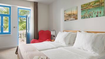 Une chambre d’hôtel avec deux lits, une chaise rouge, une table et un tableau au mur.
