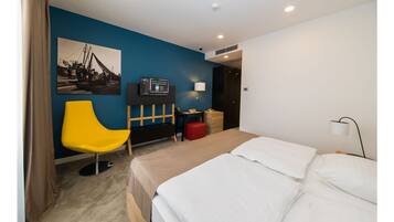 A hotel room with a bed, a desk, a chair, a television, and a picture on the wall.