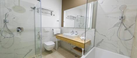 A modern bathroom with a glass-enclosed shower, a white toilet, a wooden vanity, and a large mirror.