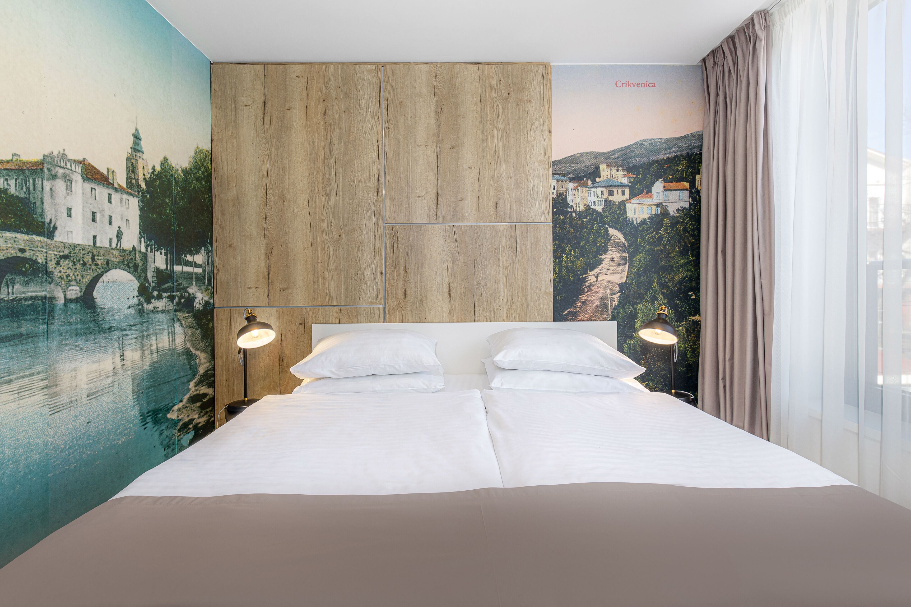 Ein Hotelzimmer mit Bett, Holz-Kopfteil und einem Wandbild einer Stadtansicht.