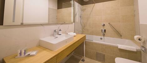 Une salle de bain moderne avec un meuble-lavabo en bois, un lavabo blanc, une cabine de douche en verre et une baignoire blanche.