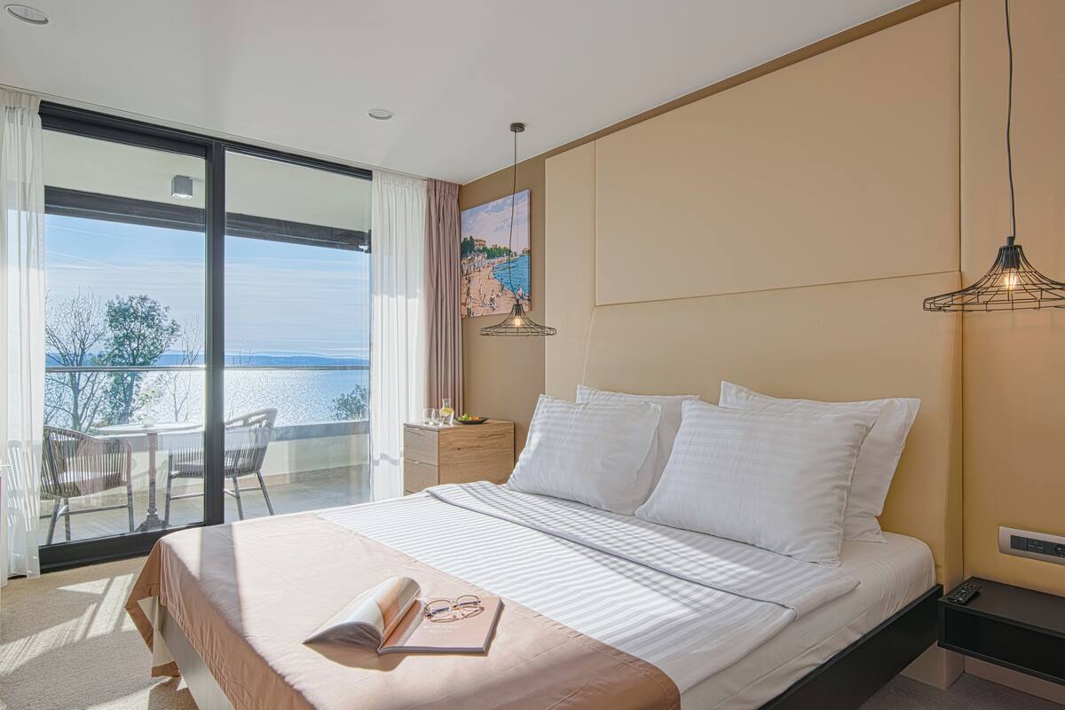 Une chambre à coucher moderne avec un grand lit, une table de chevet, un bureau et une vue sur la mer.