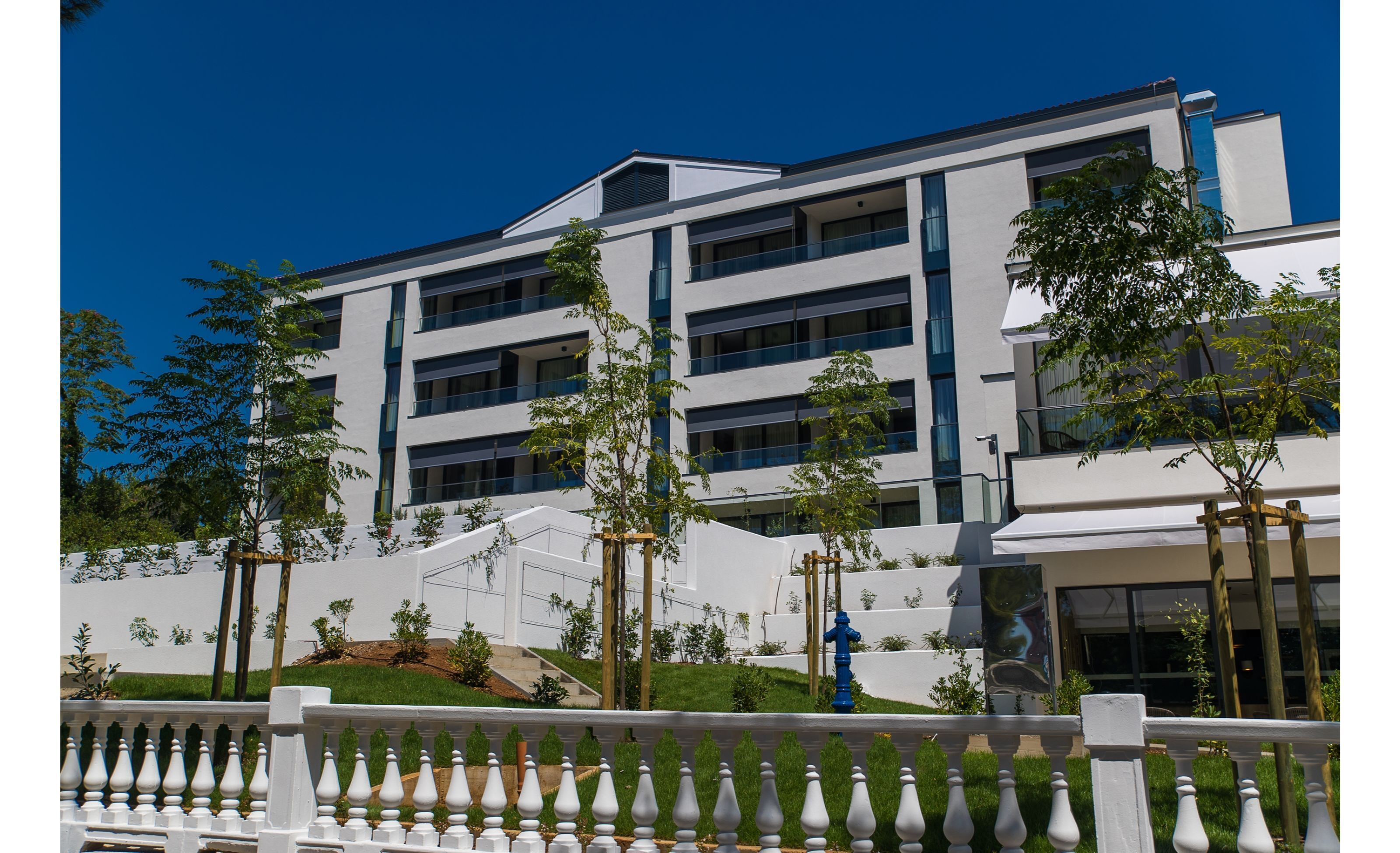 Ein mehrstöckiges Hotel mit modernem architektonischen Design, mit Balkonen und einer weißen Fassade.