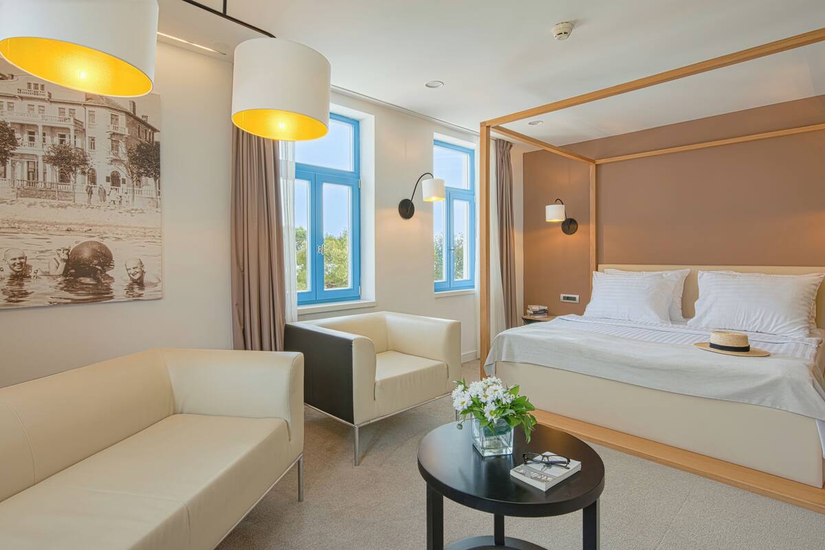 Une chambre d’hôtel moderne équipée d’un lit, d’un canapé, d’une petite table et d’une lampe fixée au mur.