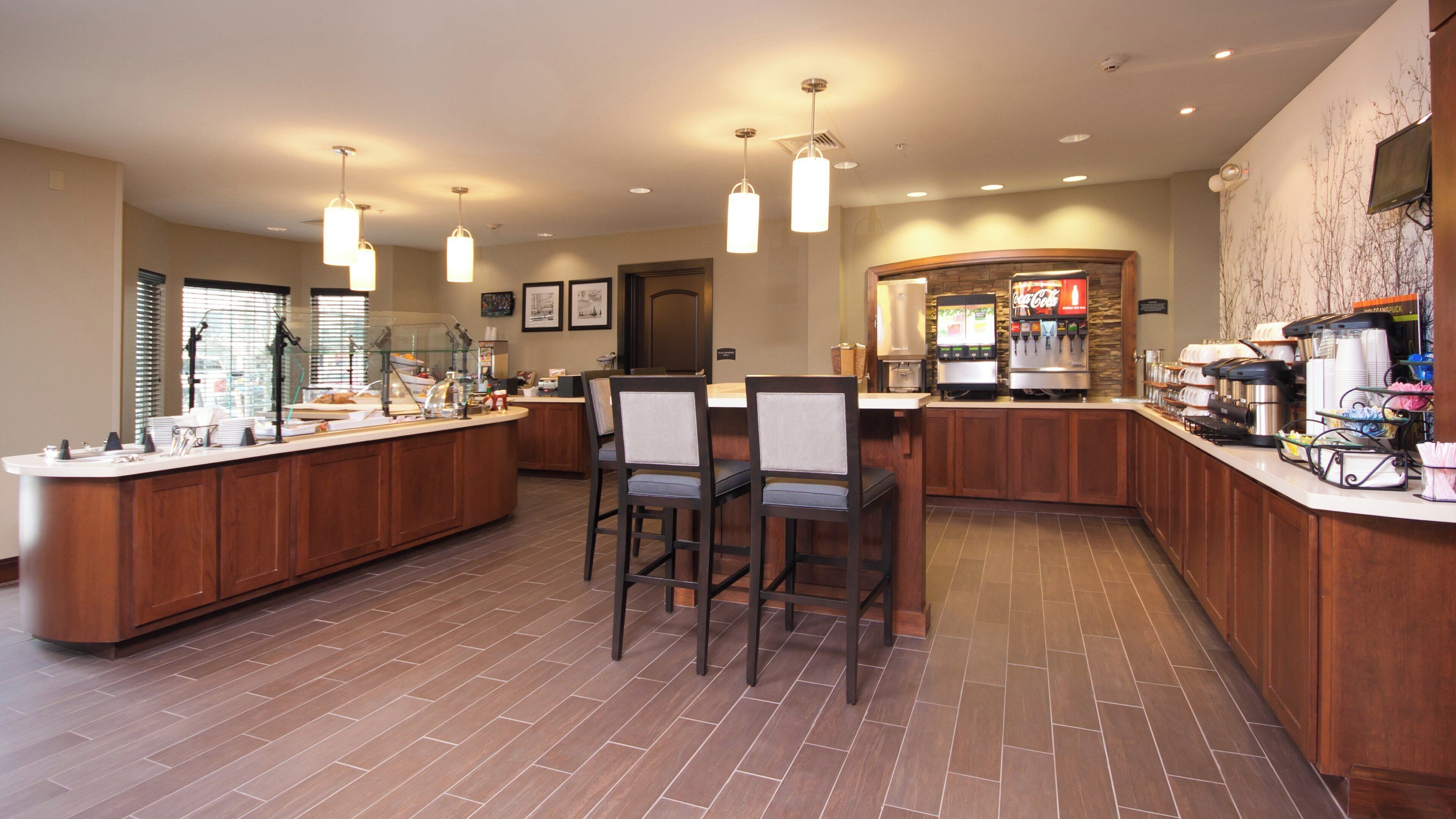 A modern kitchen with a central island, bar stools, and a coffee station.
