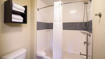 A shower with a white curtain, a toilet, and a towel rack with towels.