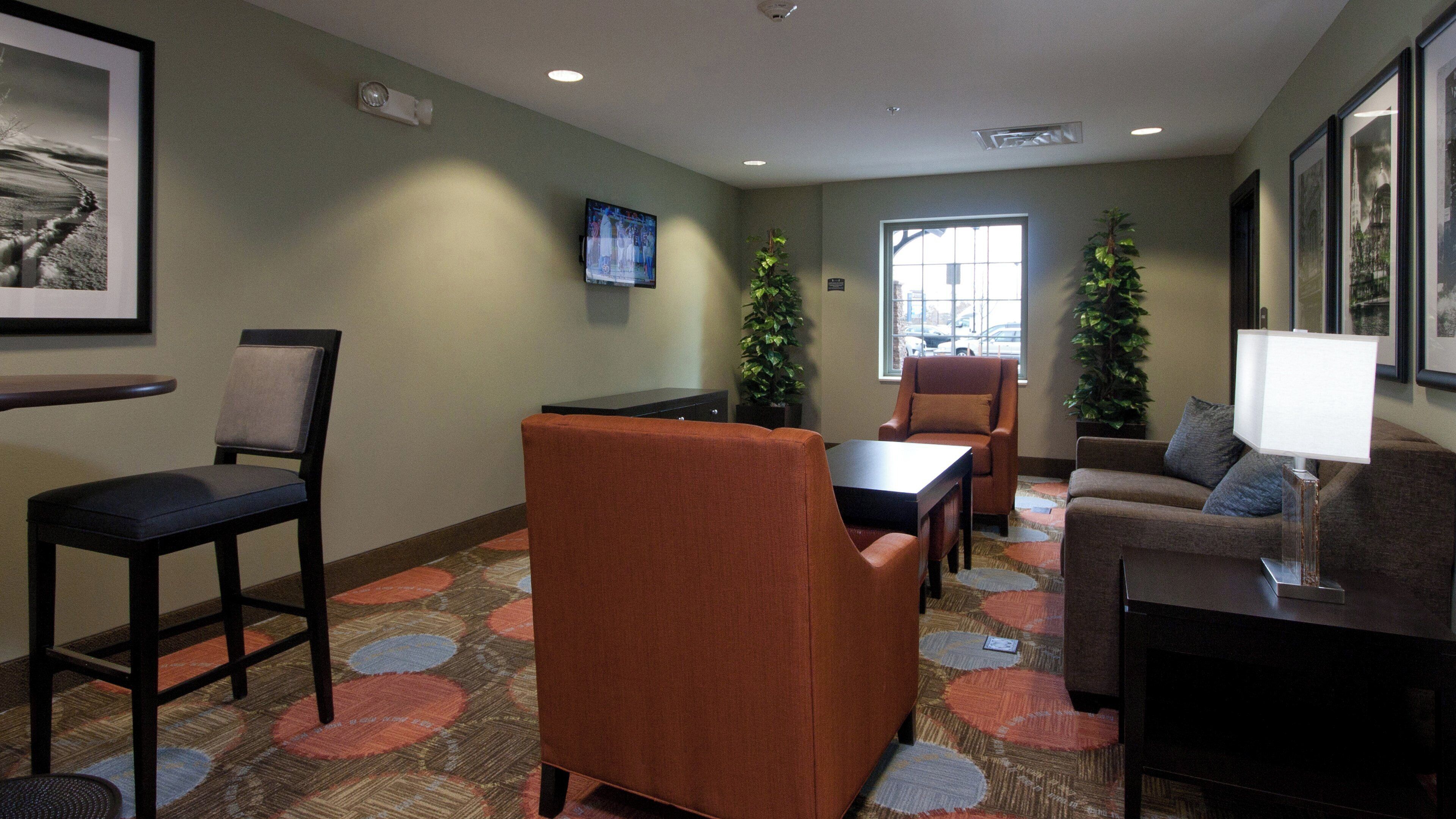 A hotel room with a seating area, a television, a window, and a Christmas tree.