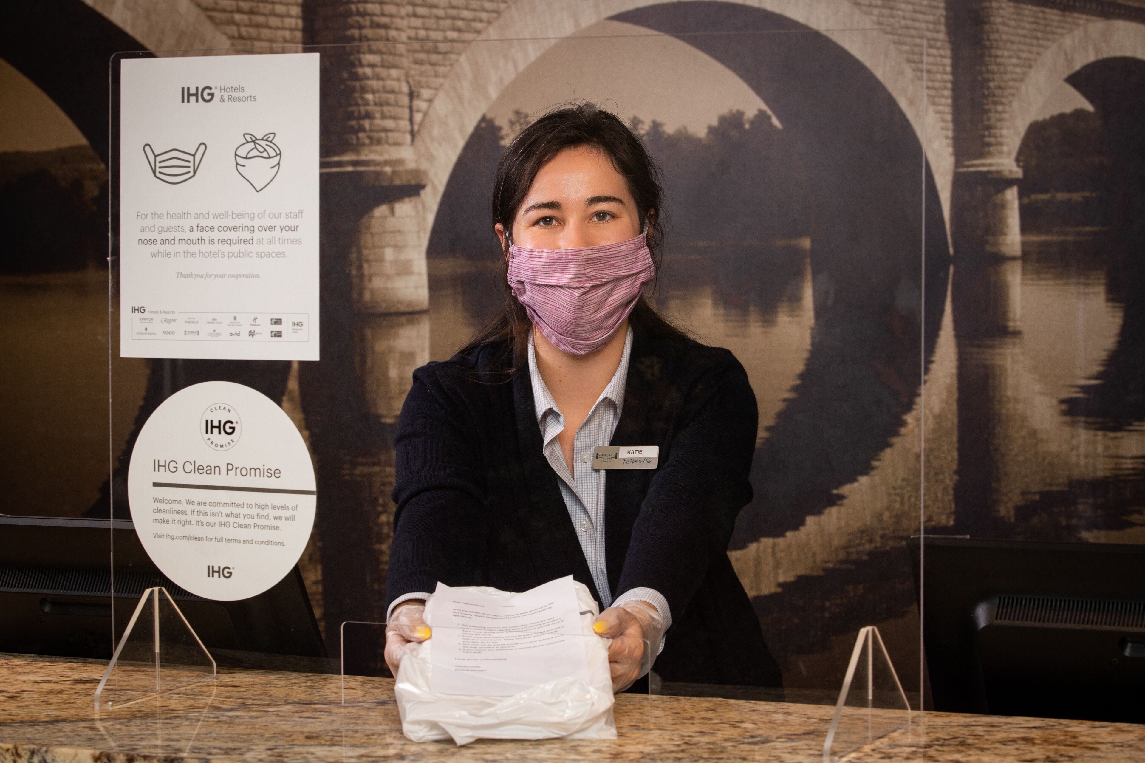 A hotel reception desk with a sign about IHG's health and cleanliness policies.
