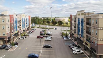 A multi-story parking structure with various cars parked, surrounded by buildings with commercial establishments.