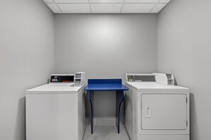 Un cuarto de lavandería con dos lavadoras y una mesa azul.