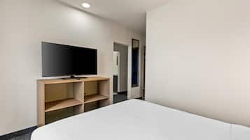 A hotel room with a bed, a TV on a wooden stand, and a mirror on the wall.