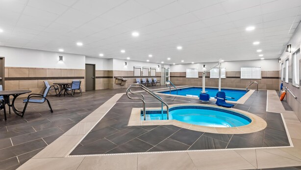 Una piscina interior con suelo de baldosas, zonas de estar e iluminación empotrada en el techo.