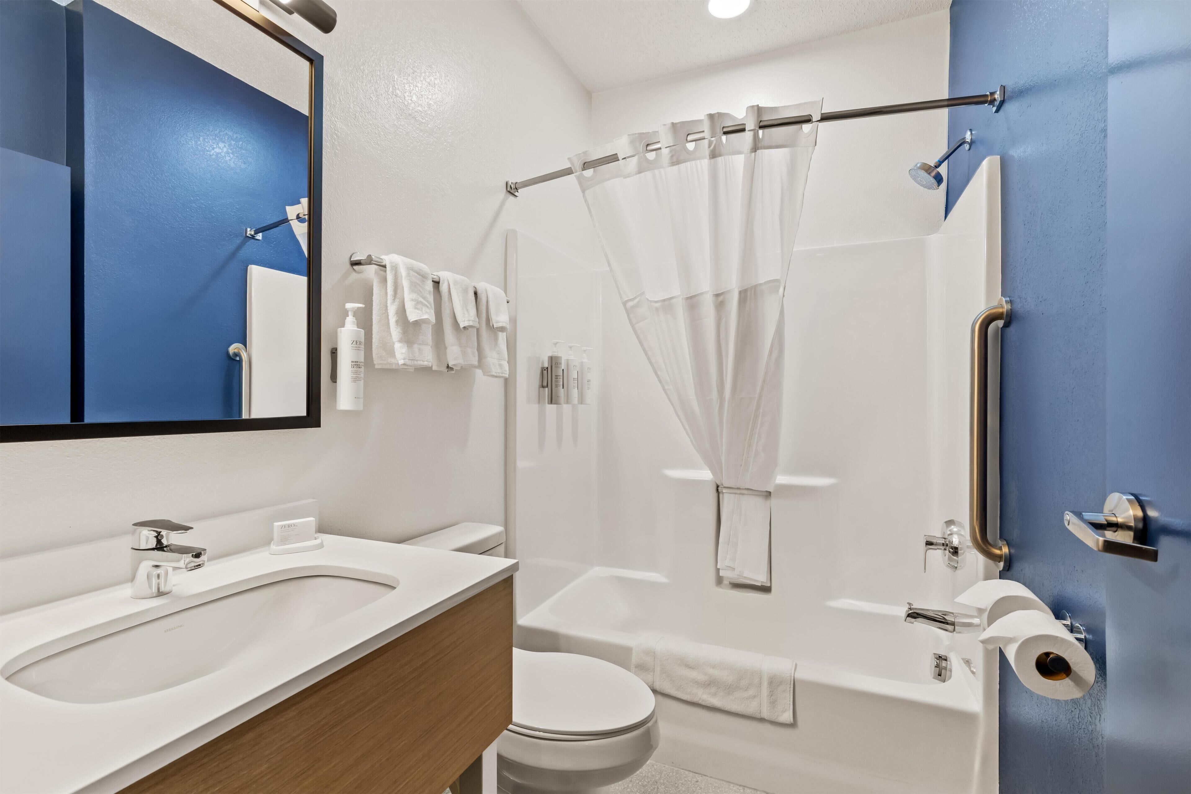 Un baño moderno con lavamanos, inodoro y zona de ducha.