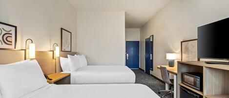 A hotel room with two beds, a desk, a television, and a microwave.